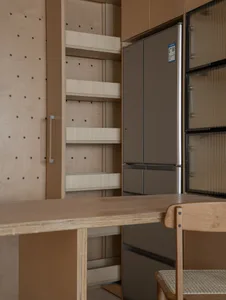 Modern wooden kitchen featuring built-in shelves and a sleek, contemporary refrigerator.