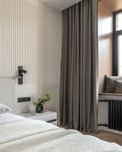 A minimalist bedroom featuring textured upholstery, grey curtains, and wooden panels.