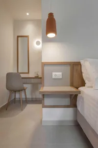 A minimalist bedroom featuring wood walls, a concrete floor, and a metal headboard.