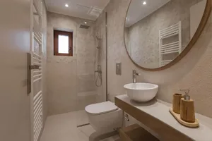 Modern bathroom with walls and floor tiled in a neutral color with a white sink and toilet.