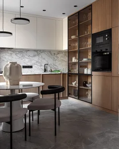 Modern kitchen featuring marble countertops, wooden cabinets, and black pendant lights.