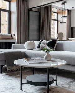 A modern living room featuring concrete coffee table, wool cushions, and metal coffee table.
