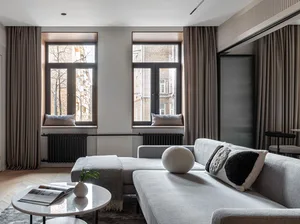 Modern living room with a grey sofa, round marble coffee table, fabric cushions, and a metal frame.