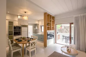 Modern minimalist kitchen with concrete countertops, wood composite flooring, and white cabinets.