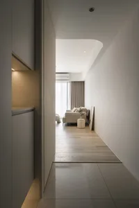 A minimalist interior space featuring wood paneling, with a view of a living area in the background.