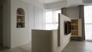 Minimalist living room with concrete walls and floor, curved furniture, and large windows with sheer curtains.