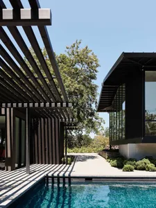 Modern architectural structure featuring black metal elements and a pergola.