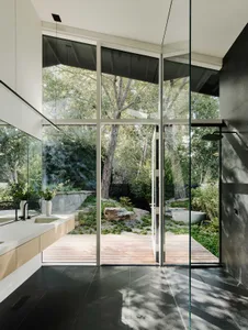 Modern bathroom featuring a glass wall, wooden elements, and stone accents.