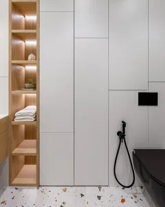 Modern minimalist bathroom with wood shelves, white cabinets, and terrazzo floor tiles.