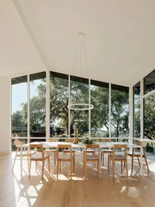 A modern interior design featuring a dining table with chairs and a pendant light hanging from the ceiling, surrounded by lar