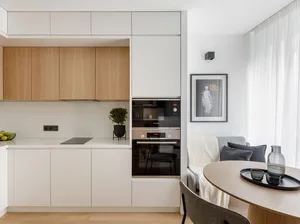 Modern kitchen and living space featuring a sleek, white, minimalist design with wooden accents.