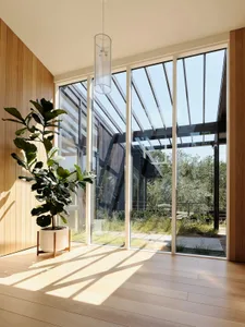 A modern living room featuring large glass windows and wooden flooring.
