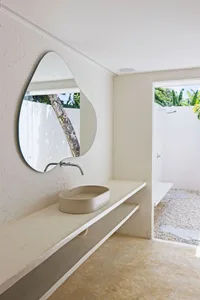 Modern minimalist bathroom featuring a concrete countertop and a leaf-shaped mirror.