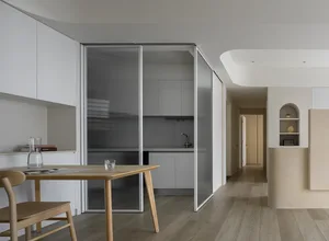 Modern minimalist white kitchen with wooden table and chairs.