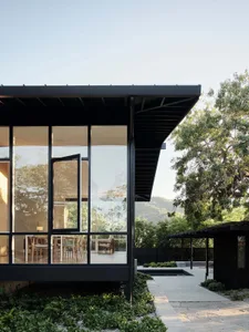 Modern residential exterior featuring large glass panels and metal structural elements.