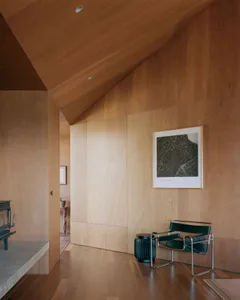 Modern minimalist room with wooden walls and a black chair.