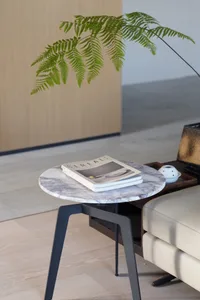 A minimalist marble side table in a modern living room setting.
