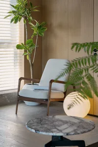 Modern living room featuring marble accents, wood furniture, fabric seating, and potted plants.