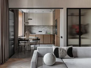 A modern minimalist living room with a grey sofa, black and white throw pillow, and a small round white cushion.