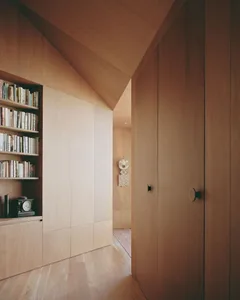 A modern minimalist residential closet featuring wooden shelves and doors.
