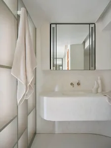A minimalist bathroom with a concrete sink and a large mirror above it.