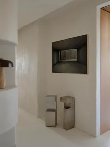 An entryway featuring metallic stools and concrete walls, creating a modern and minimalist atmosphere.