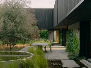 Modern backyard featuring wooden furniture and concrete pavers.