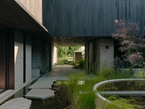 A modern residential entryway featuring a black panel wall, concrete steps, and a water feature.