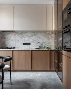 A modern kitchen with marble countertops, wooden cabinets, and a round dining table.