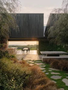 A modern exterior space with concrete and wood materials surrounded by green foliage.