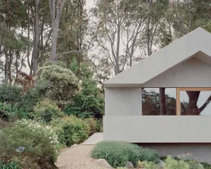 A minimalist concrete house exterior surrounded by lush greenery and trees.