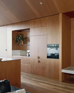 Modern residential kitchen featuring sleek wood cabinets and a floating shelf above the countertop.