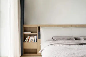 A minimalist bedroom featuring a wooden bookshelf with a bookcase and a modern bed with a cushioned headboard.