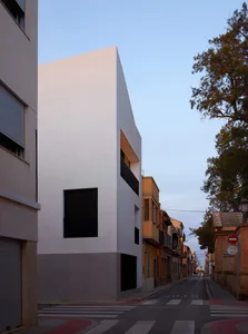 A minimalist concrete building with a modern design stands on a quiet street.