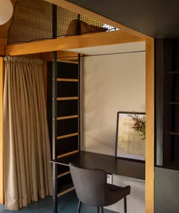 A minimalist home office featuring a black desk, grey chair, wooden shelves, and a framed piece of art.