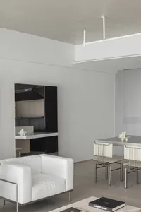 Contemporary minimalist living room features a sleek white leather sofa with metallic frame and black wall panels.