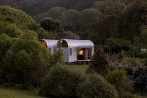A modern house with corrugated metal exterior surrounded by trees.