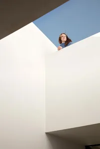 A minimalist modern interior featuring white concrete walls with a large skylight.
