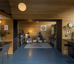 A modern living room featuring wood flooring and wood-paneled walls.