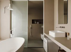 Minimalist bathroom with a white bathtub, concrete walls, and a floating vanity with a white sink.