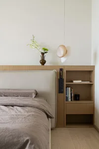 Modern, minimalist bedroom featuring wooden furniture and a vase with orchids.