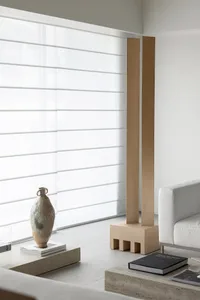 A minimalist living room with a white sofa, concrete coffee table, and large windows.