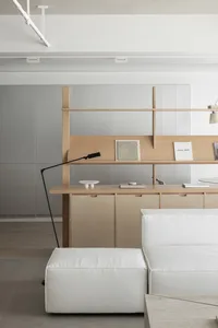 A minimalist living room featuring modern furniture, white leather and marble surfaces, and wood shelves.