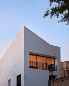 Modern residential house with concrete exterior and large windows.