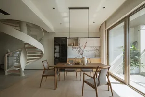 A modern residential kitchen featuring wooden furniture and a spiral staircase.