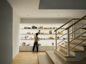 A modern, industrial-style living room with metal shelves and wooden stairs.