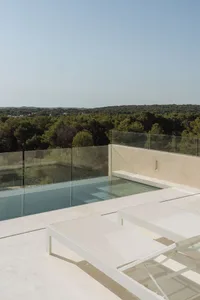 Modern outdoor lounge area with glass railings and concrete patio.