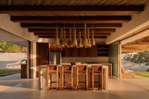 Modern residential kitchen featuring wood finishes and a bar counter with stools.