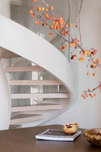 A modern white staircase with wooden steps and glass railings.
