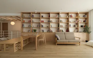 A modern living room with a wooden floor, a light-colored sofa, and a large wooden bookshelf filled with books.